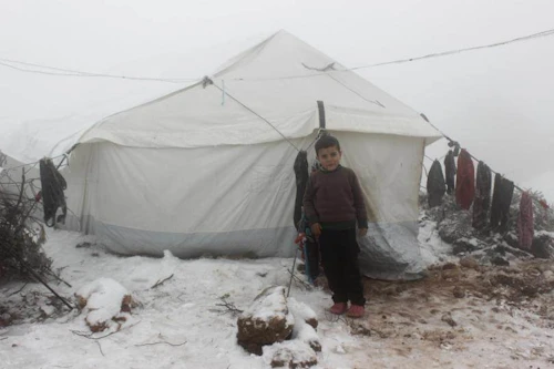 Þessi ungi drengur stendur við tjald fjölskyldu sinnar sem er á vergangi vegna átaka í Sýrlandi. Veturinn er kominn eins og sjá má. © UNICEF/Alshami